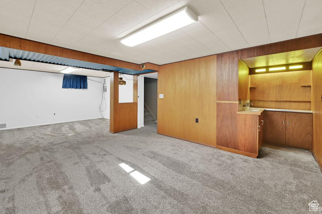 Finished basement with carpet flooring, wooden walls, and stairway
