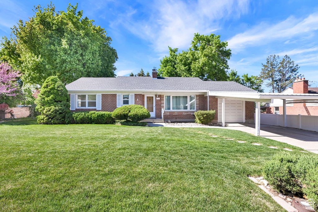 Single story home featuring an attached garage, brick siding, a chimney, and concrete driveway