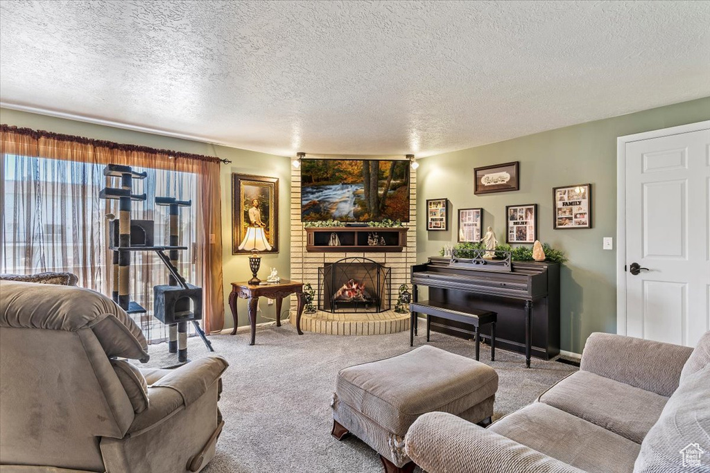Carpeted living area featuring a fireplace, a textured ceiling, and baseboards