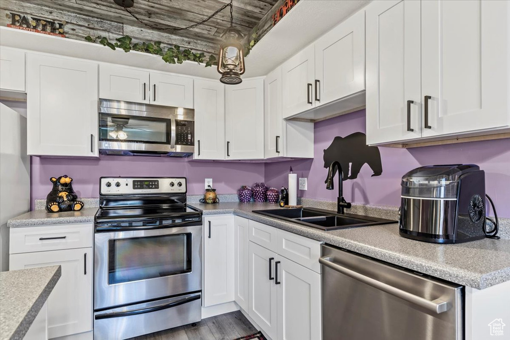 Kitchen featuring appliances with stainless steel finishes, a sink, and white cabinetry