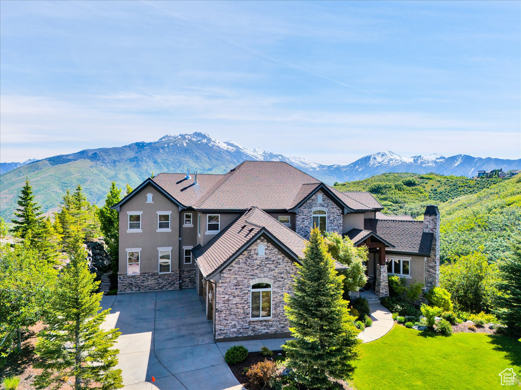 View of front of property with stone siding, stucco siding, a mountain view, and driveway