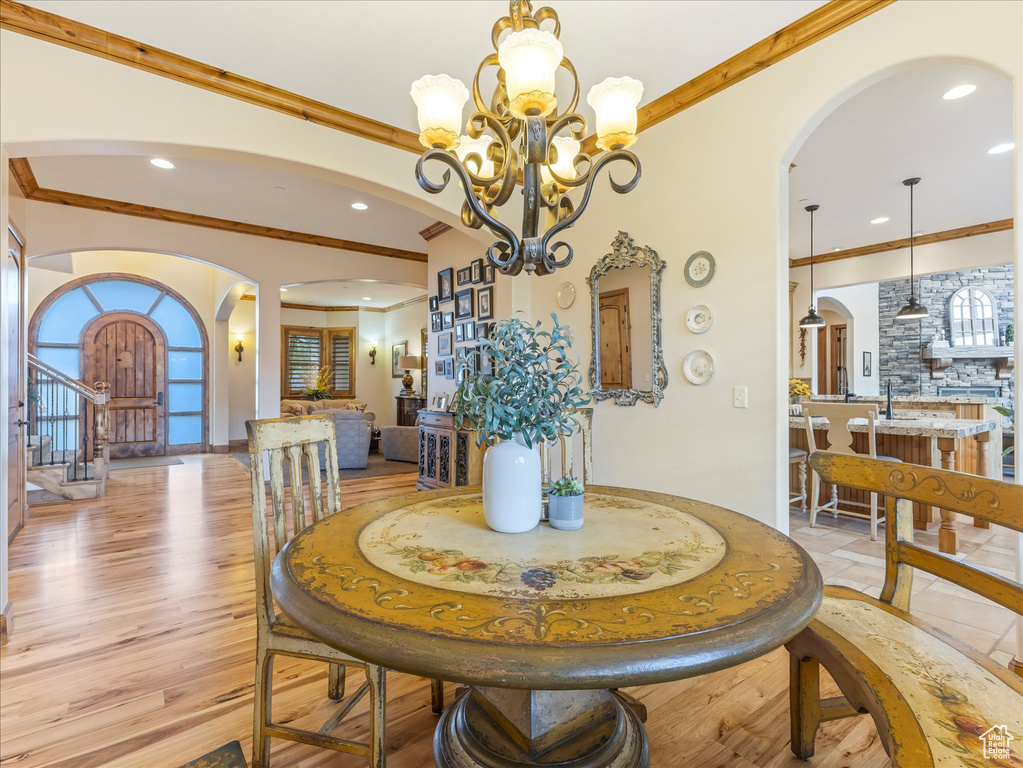 Dining area featuring arched walkways, crown molding, a chandelier, recessed lighting, and stairway