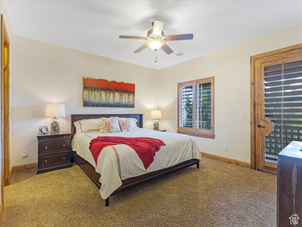 Carpeted bedroom featuring baseboards, a ceiling fan, and access to exterior