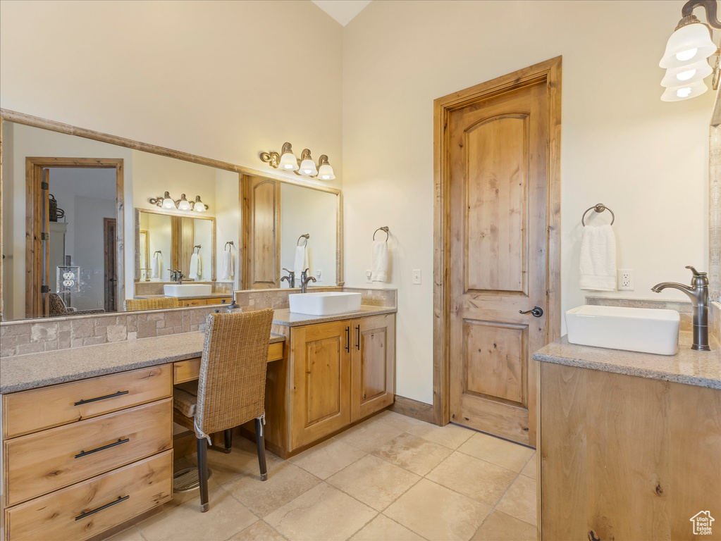 Bathroom featuring vanity, tile patterned flooring, and vaulted ceiling