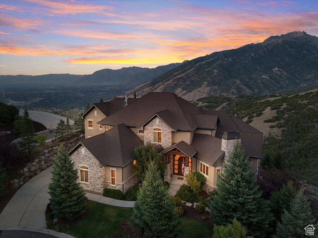 View of front of home featuring stone siding, a mountain view, stucco siding, and concrete driveway