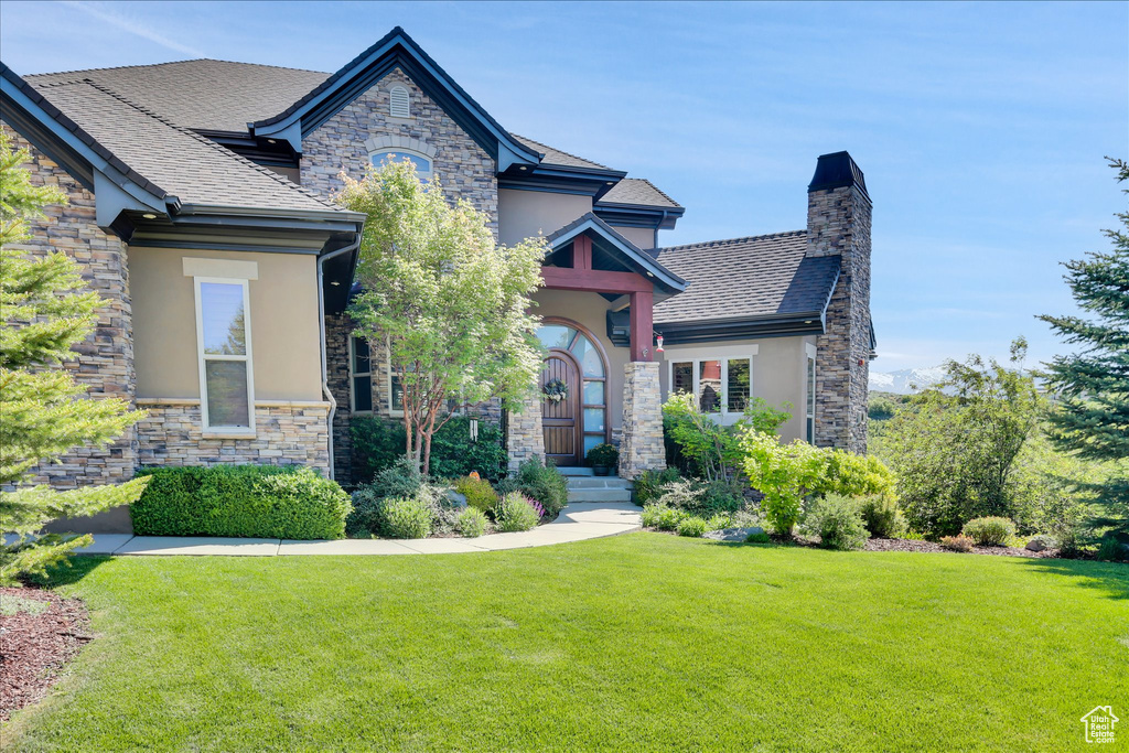 View of front facade with stucco siding, stone siding, and a front lawn