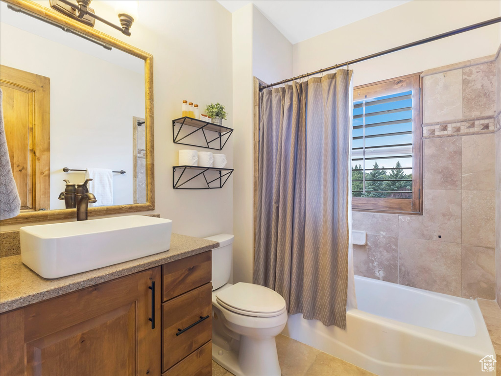 Bathroom featuring toilet, vanity, and shower / bathtub combination with curtain