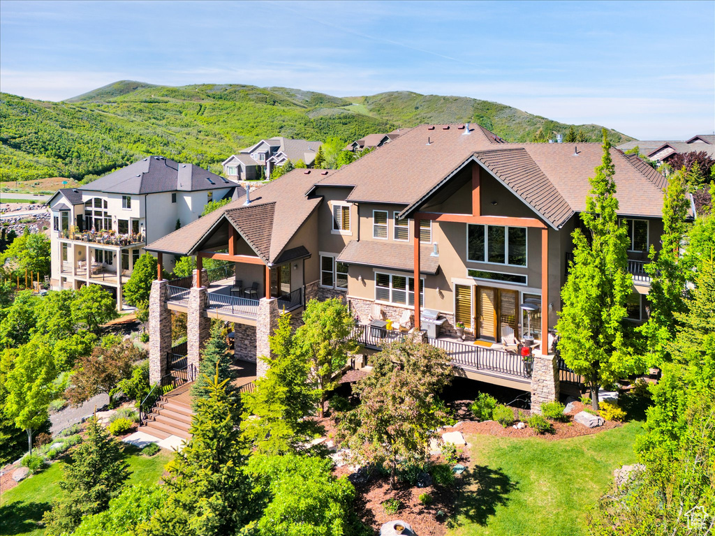 Back of house with stucco siding, stone siding, a mountain view, a residential view, and stairs