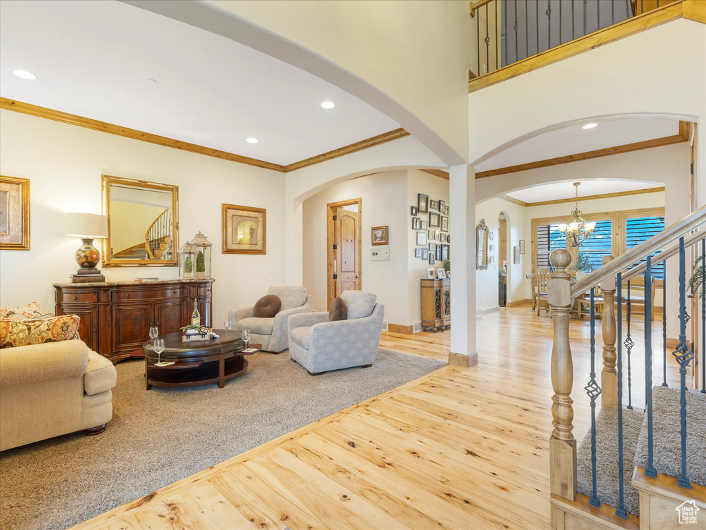 Living area featuring arched walkways, wood finished floors, a chandelier, ornamental molding, and recessed lighting