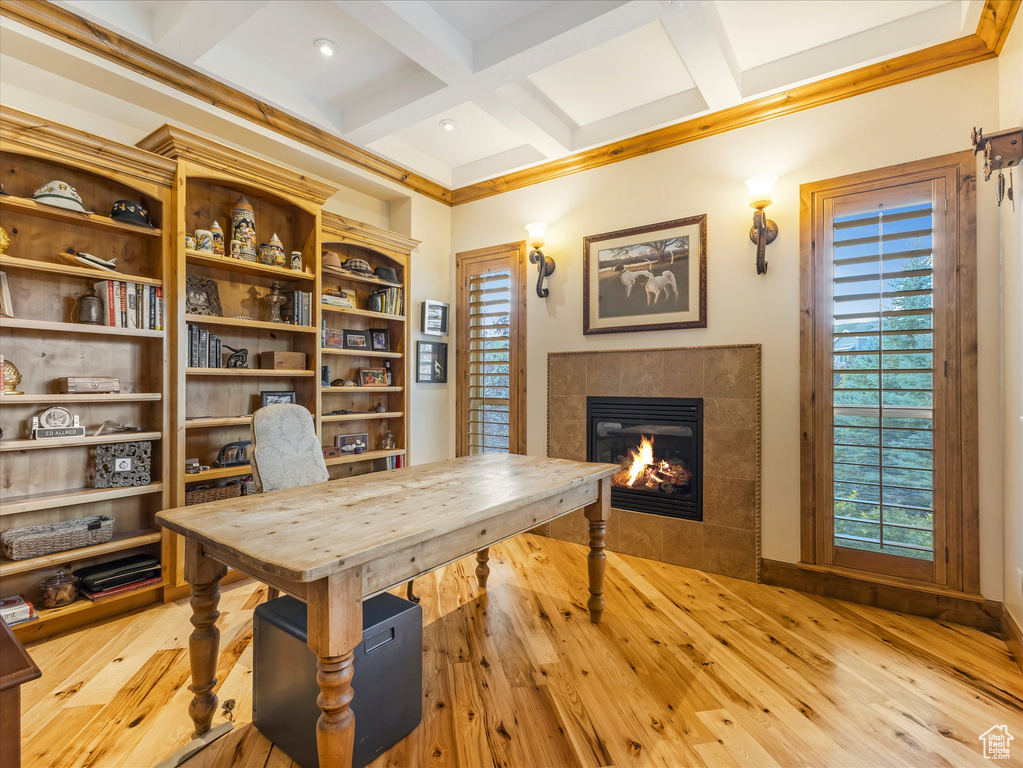 Home office featuring a tiled fireplace, coffered ceiling, light wood finished floors, and beam ceiling