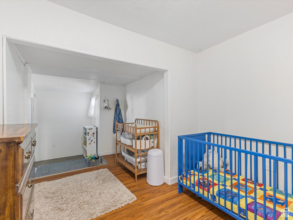 Bedroom with wood finished floors, baseboards, and a crib