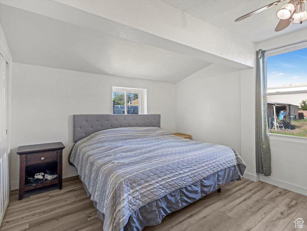 Bedroom featuring wood finished floors, a ceiling fan, lofted ceiling, and baseboards