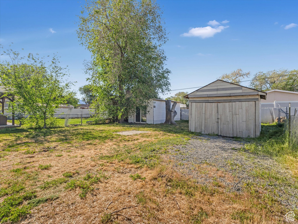 Fenced backyard featuring a storage shed and an outbuilding