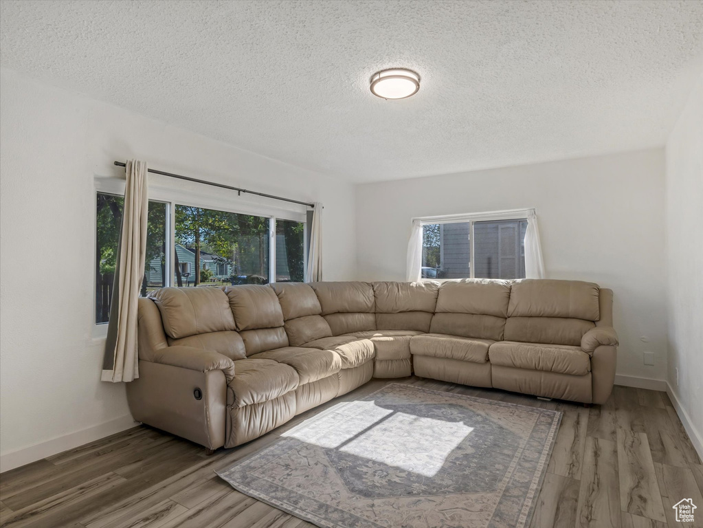 Living room with a textured ceiling, wood finished floors, and baseboards