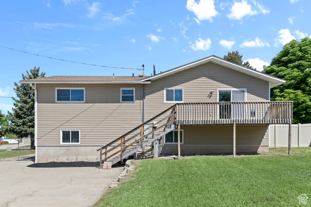 Rear view of property featuring a lawn, a deck, and stairs