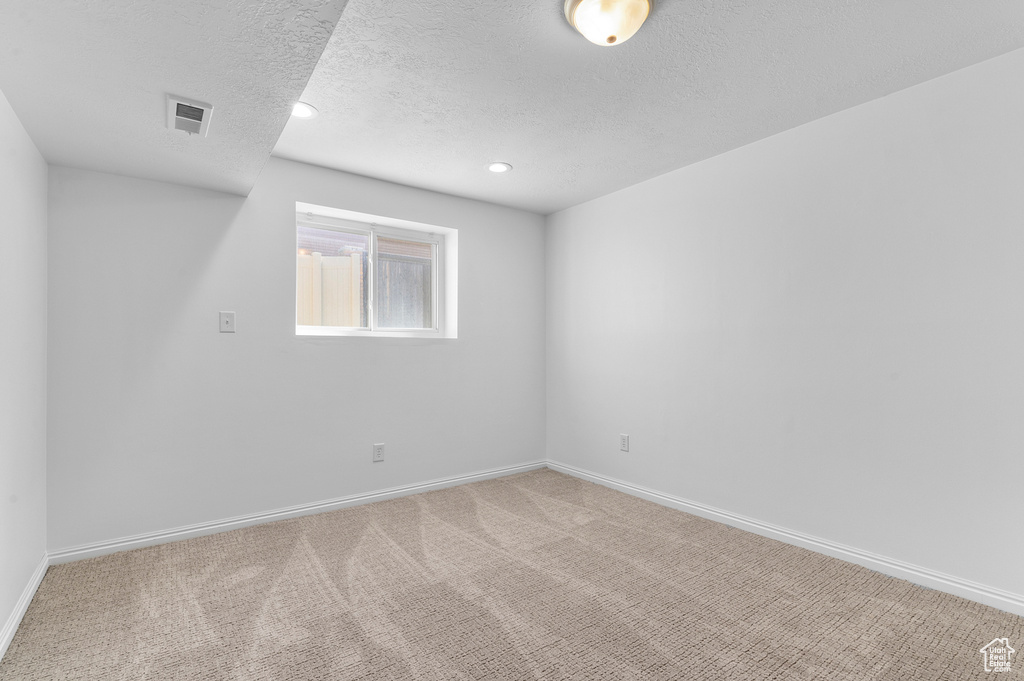 Carpeted empty room with a textured ceiling, baseboards, and recessed lighting