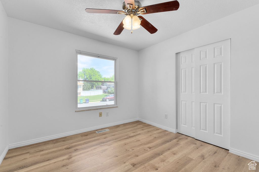 Unfurnished room featuring ceiling fan, light wood finished floors, and baseboards