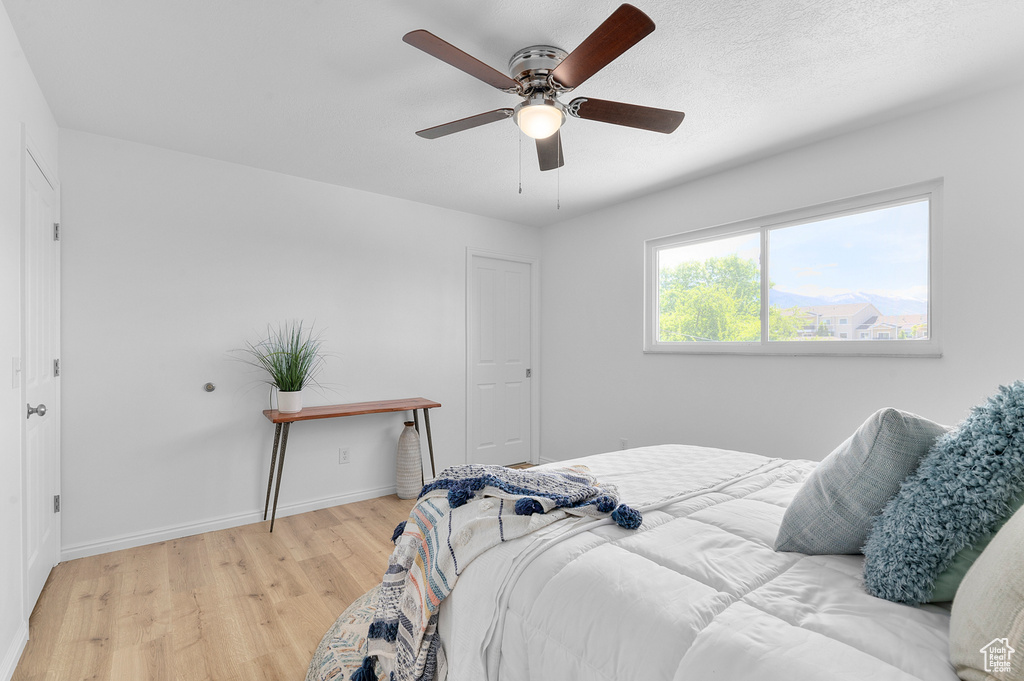 Bedroom with light wood-type flooring, baseboards, and ceiling fan