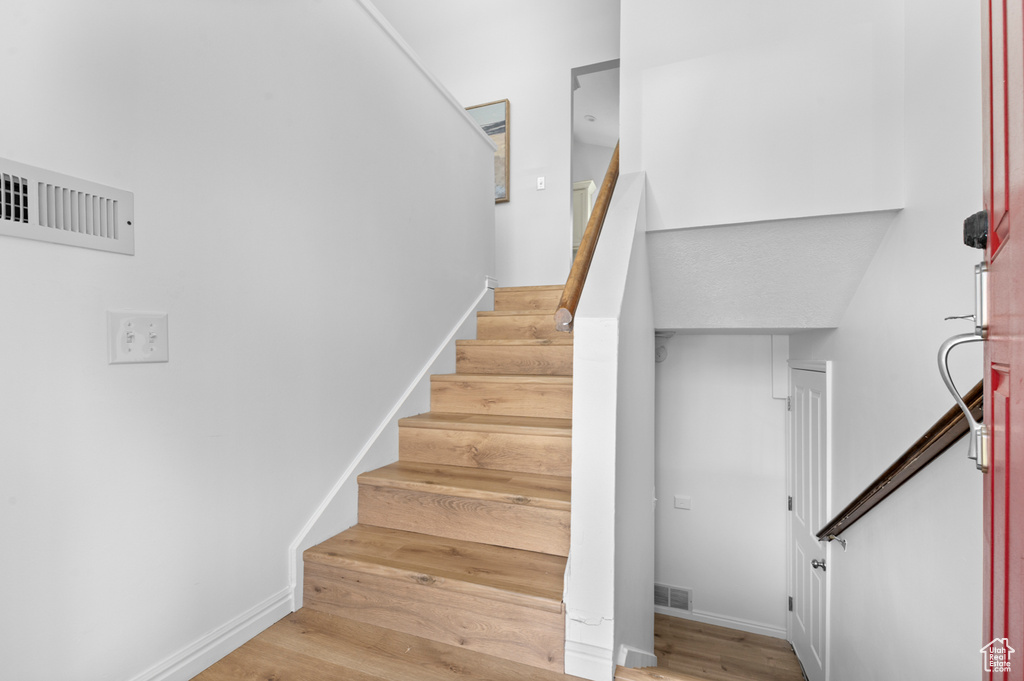 Stairway with wood finished floors and baseboards