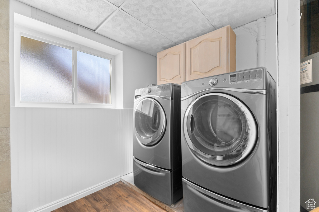 Laundry room with washing machine and clothes dryer, wood finished floors, and cabinet space