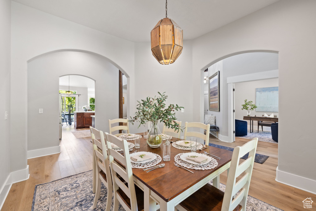 Dining space featuring arched walkways, light wood-style flooring, and baseboards