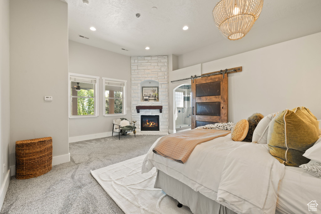 Bedroom with carpet flooring, baseboards, a stone fireplace, a barn door, and recessed lighting