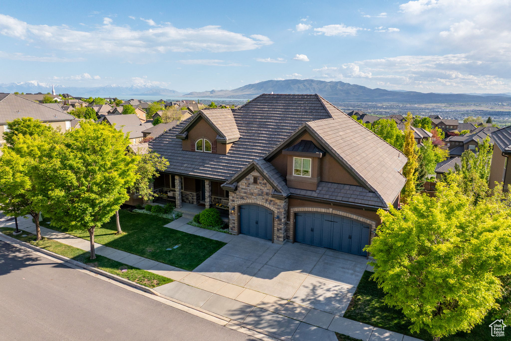 View of front facade with stone siding, driveway, a mountain view, and a residential view