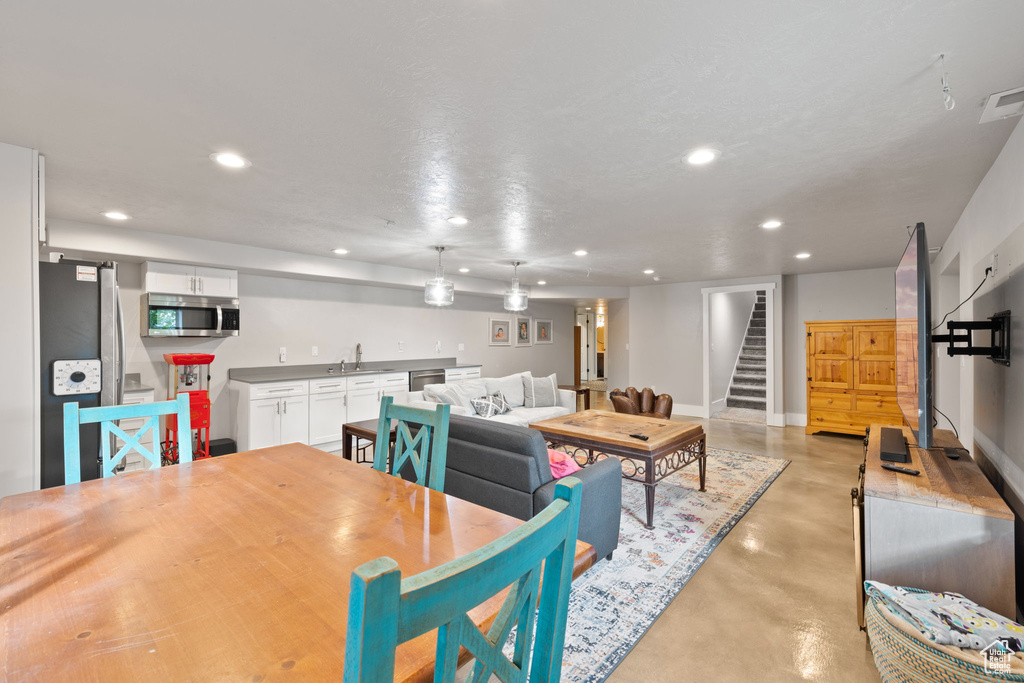 Dining space with finished concrete flooring, stairway, recessed lighting, baseboards, and bar