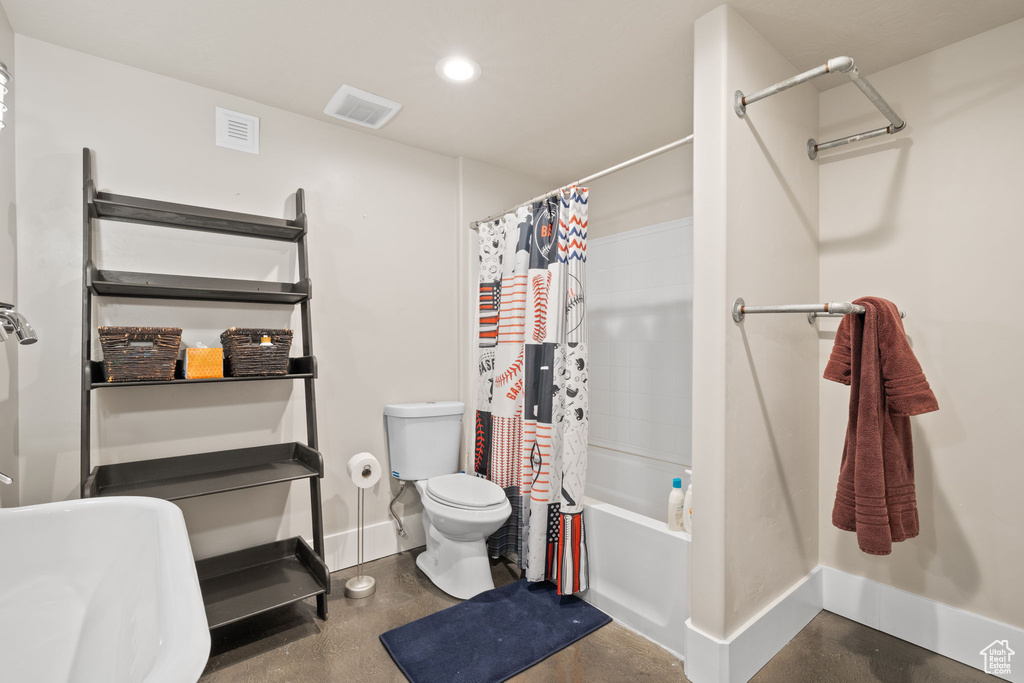 Bathroom with toilet, recessed lighting, shower / bath combo, finished concrete floors, and baseboards