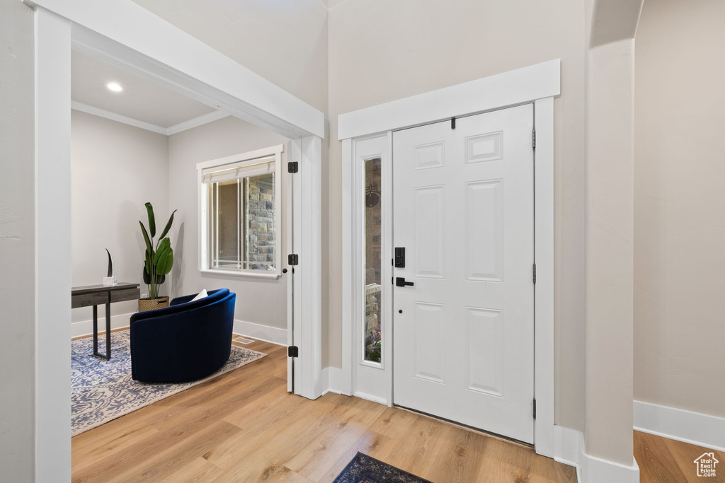 Foyer entrance with wood finished floors, baseboards, ornamental molding, and recessed lighting