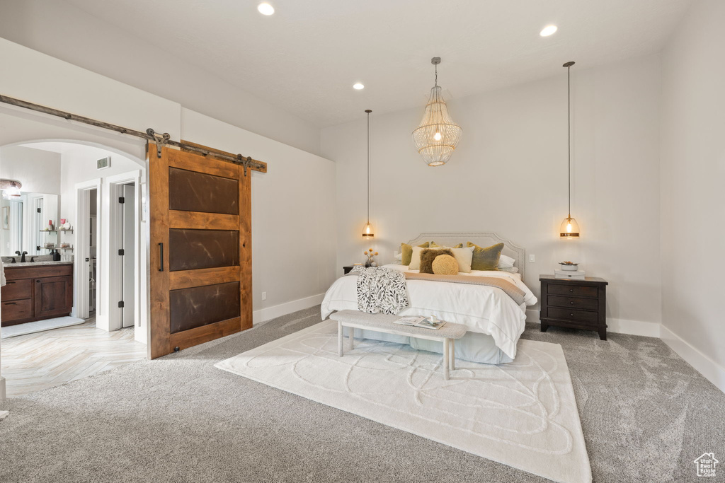 Bedroom featuring a barn door, arched walkways, recessed lighting, baseboards, and a sink