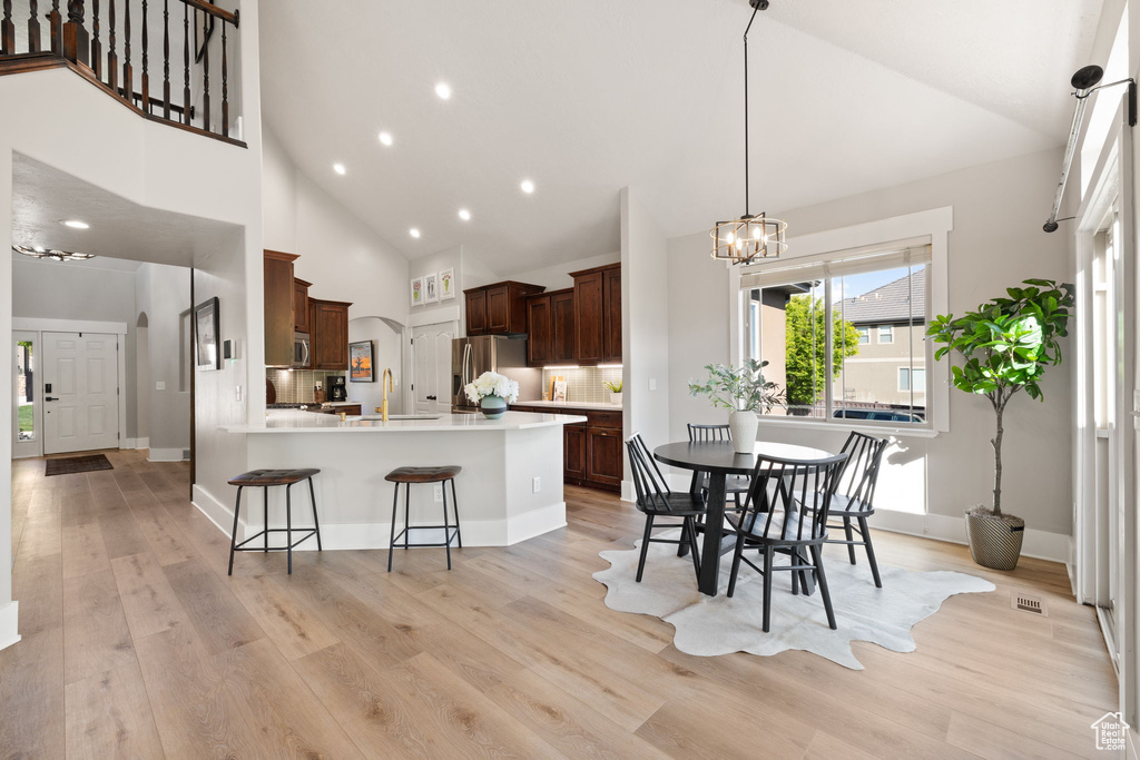 Kitchen featuring appliances with stainless steel finishes, a kitchen breakfast bar, a chandelier, light wood-type flooring, and a peninsula