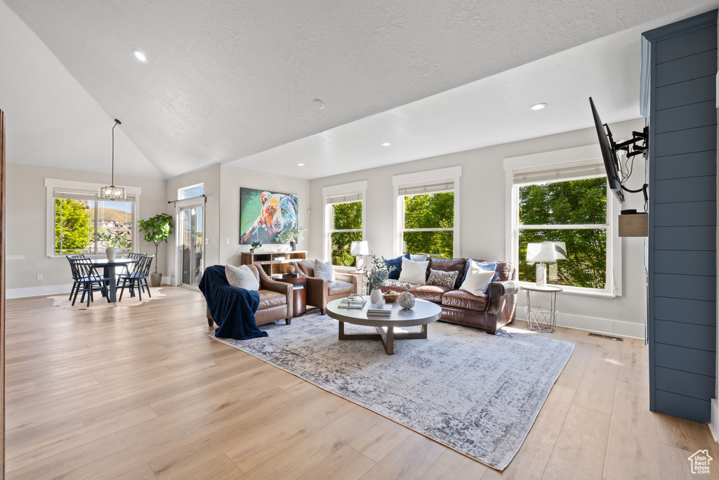 Living room featuring healthy amount of natural light, light wood-style flooring, baseboards, a textured ceiling, and recessed lighting