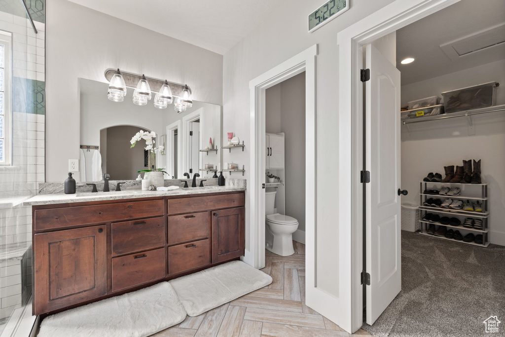 Bathroom with toilet, double vanity, and a walk in closet