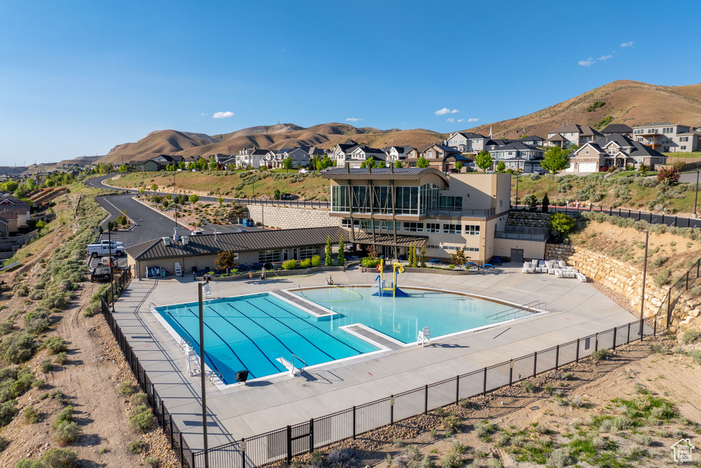 Community pool with fence, a mountain view, a residential view, and a patio area