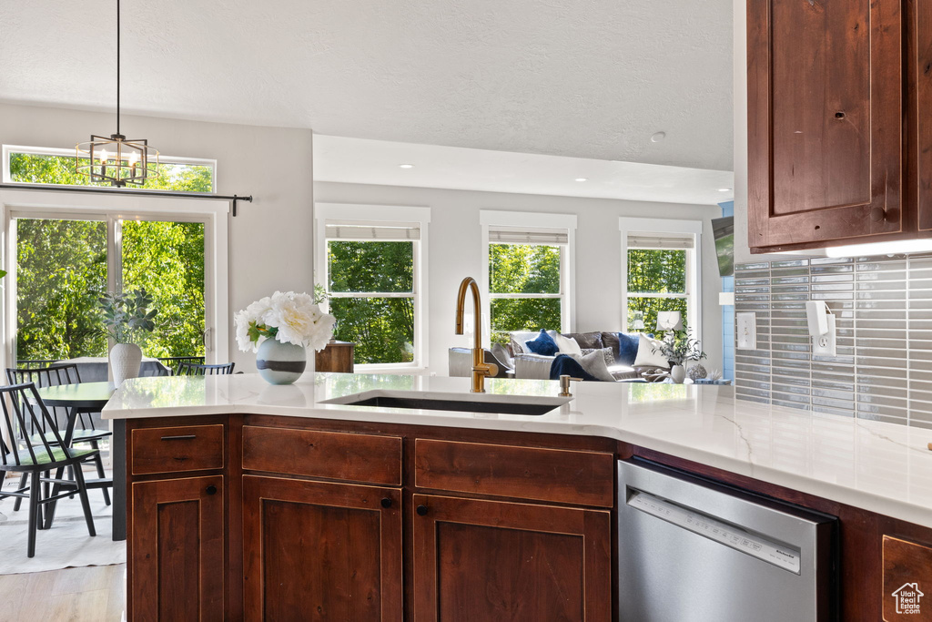 Kitchen with stainless steel dishwasher, a sink, open floor plan, decorative backsplash, and a peninsula