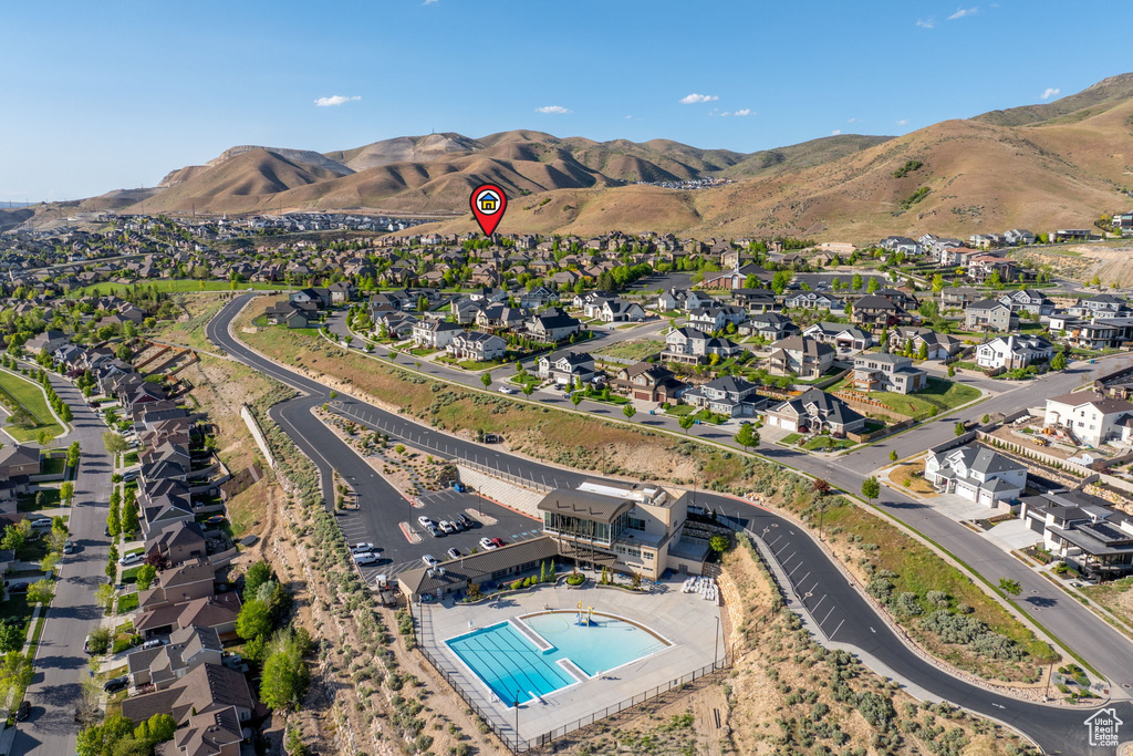 Aerial view of property's location featuring a pool area, mountains, and nearby suburban area
