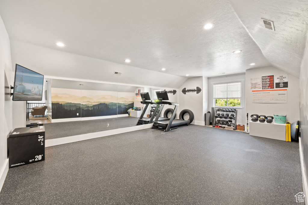 Exercise area with lofted ceiling, recessed lighting, and baseboards