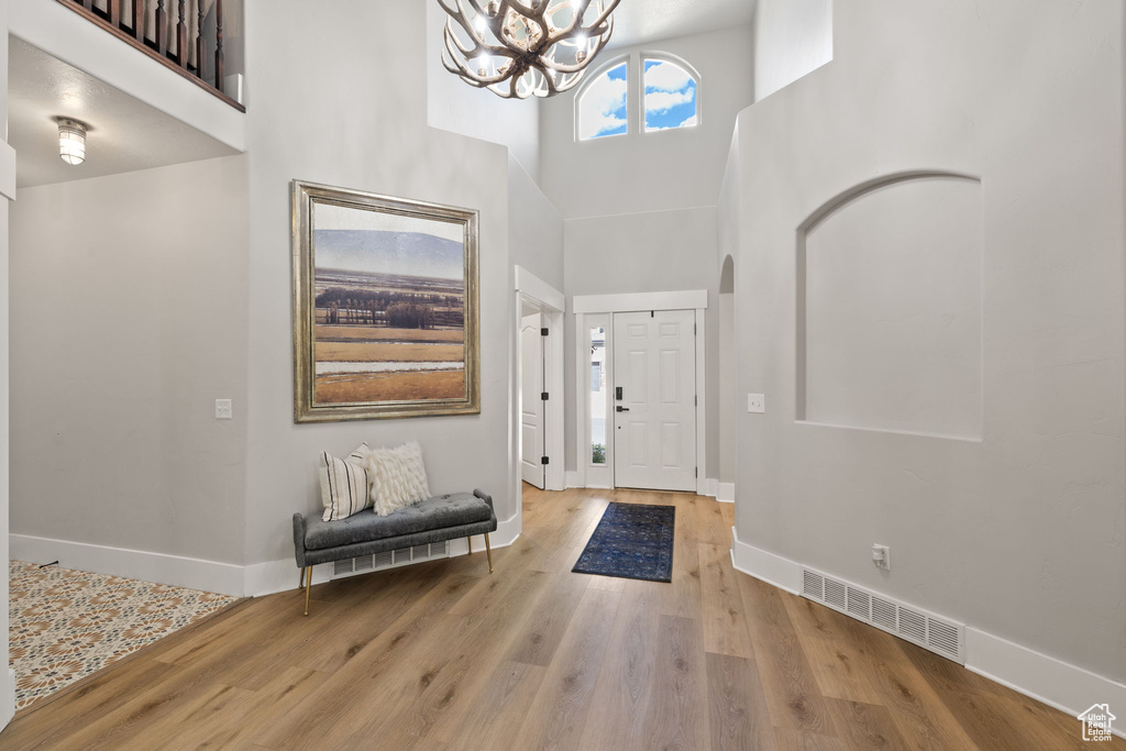 Entryway featuring a high ceiling, baseboards, a chandelier, and wood finished floors