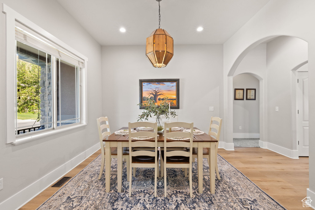 Dining room featuring arched walkways, light wood-style flooring, baseboards, and recessed lighting