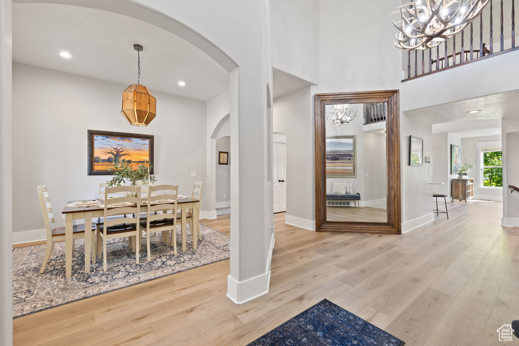 Dining room with arched walkways, light wood finished floors, baseboards, a chandelier, and recessed lighting
