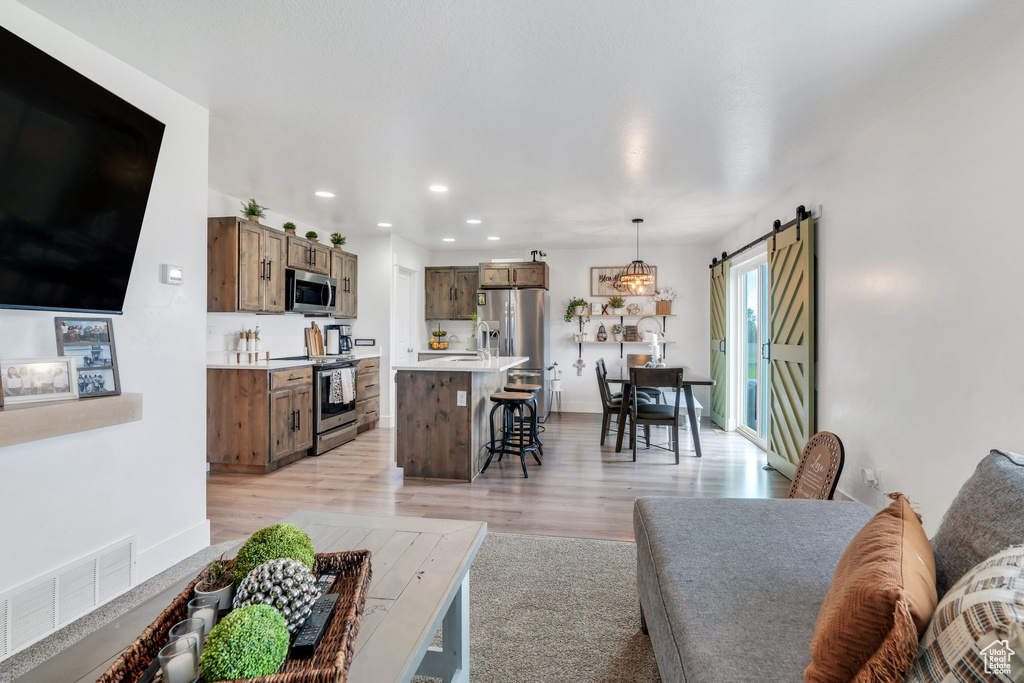Living room featuring light wood-style flooring, a barn door, and recessed lighting