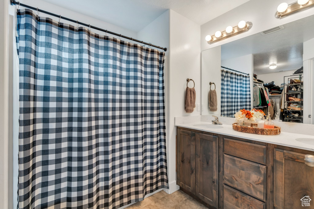 Full bath featuring double vanity, a spacious closet, a shower with curtain, and tile patterned flooring