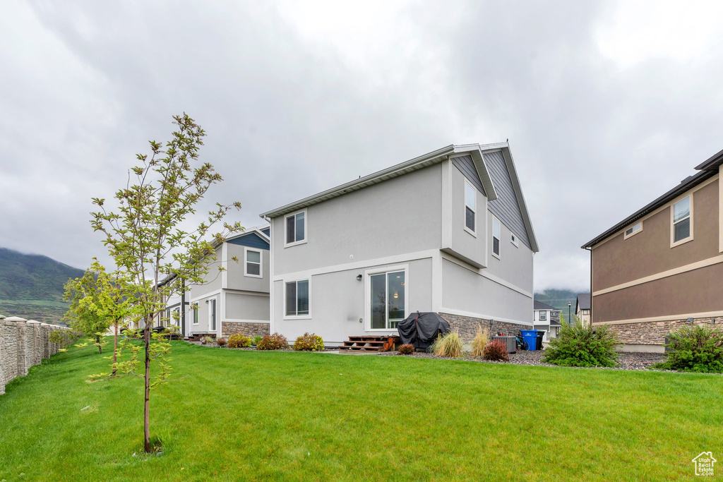 Back of property with stone siding, stucco siding, and a yard