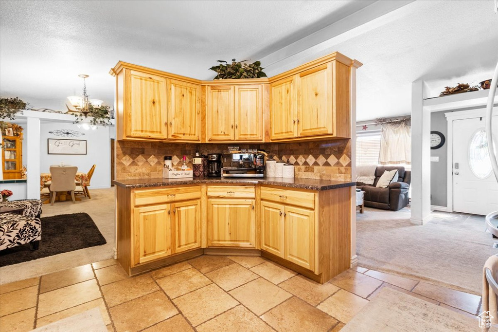 Kitchen with light colored carpet, a chandelier, and backsplash