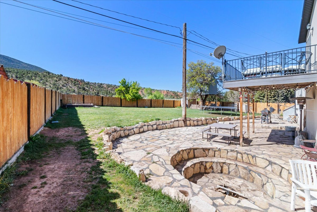 View of yard with a trampoline, a patio, and a fire pit