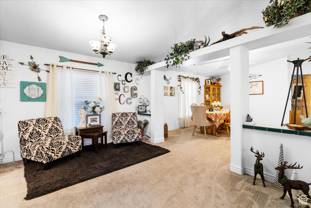 Living area featuring light colored carpet, a chandelier, and baseboards