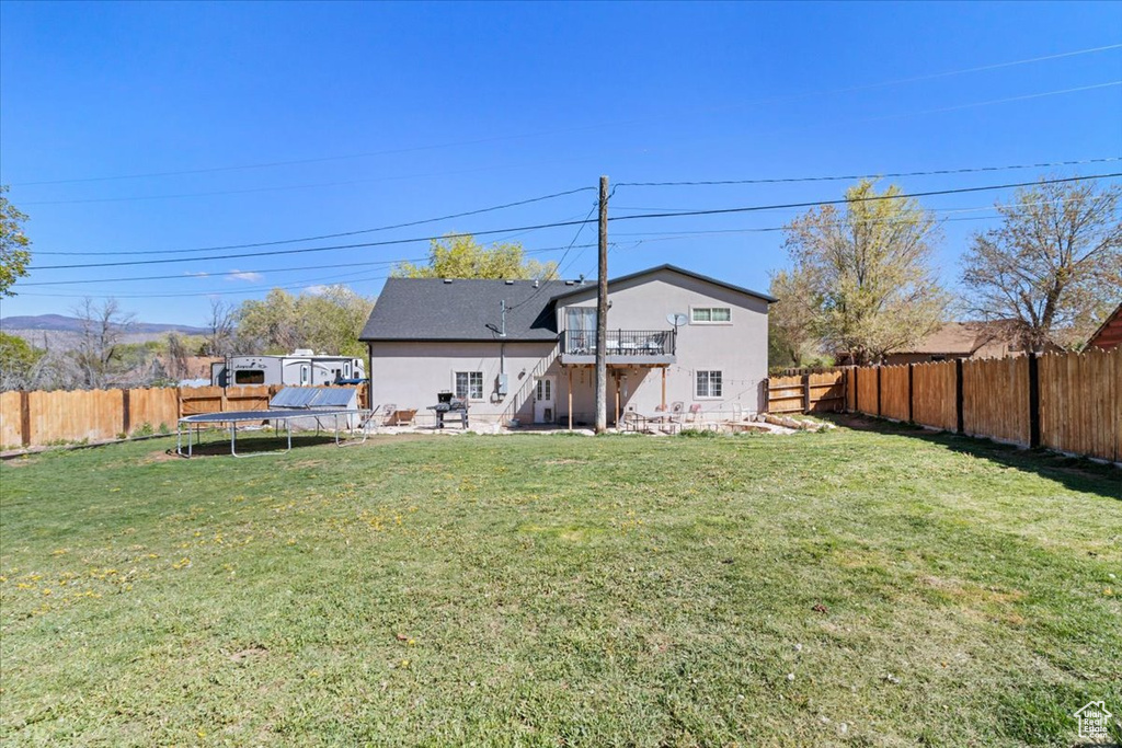 Rear view of property with a trampoline, a wooden deck, and a patio area
