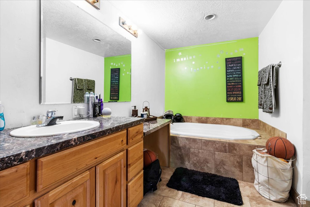 Full bathroom featuring a textured ceiling, a bath, and vanity