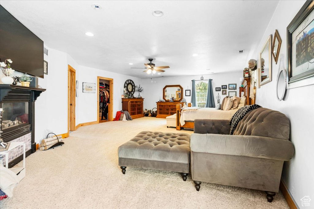Living area featuring carpet floors, a glass covered fireplace, a ceiling fan, recessed lighting, and baseboards